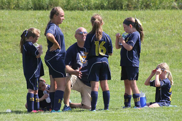 Players huddle around their volunteer coach, Vince