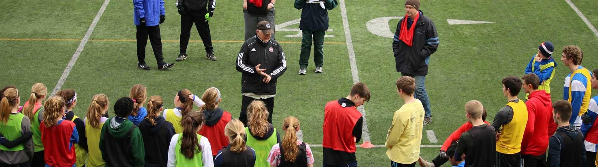 Photo of dozens of players huddled around a coach