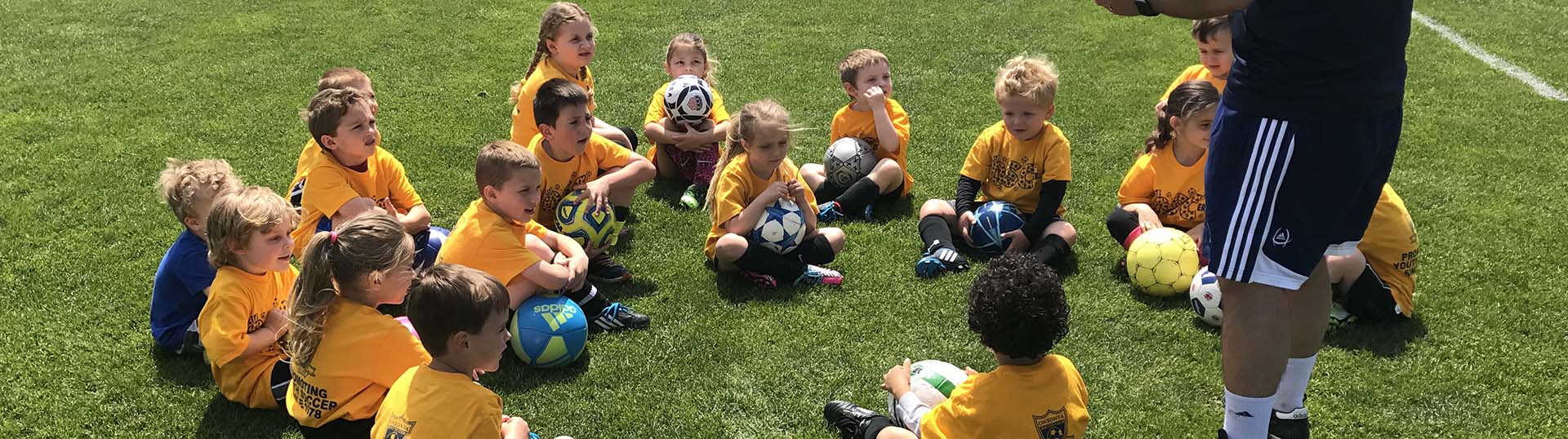 Lil OSC'ers sit in a huddle listening to their coach