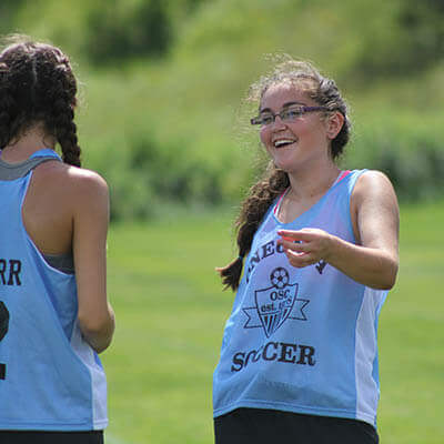 An Oneonta Soccer Club player smiles and laughs with a teammate