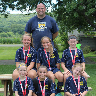 A group of teammates and their coach pose for a picture after winning second place in the tournament